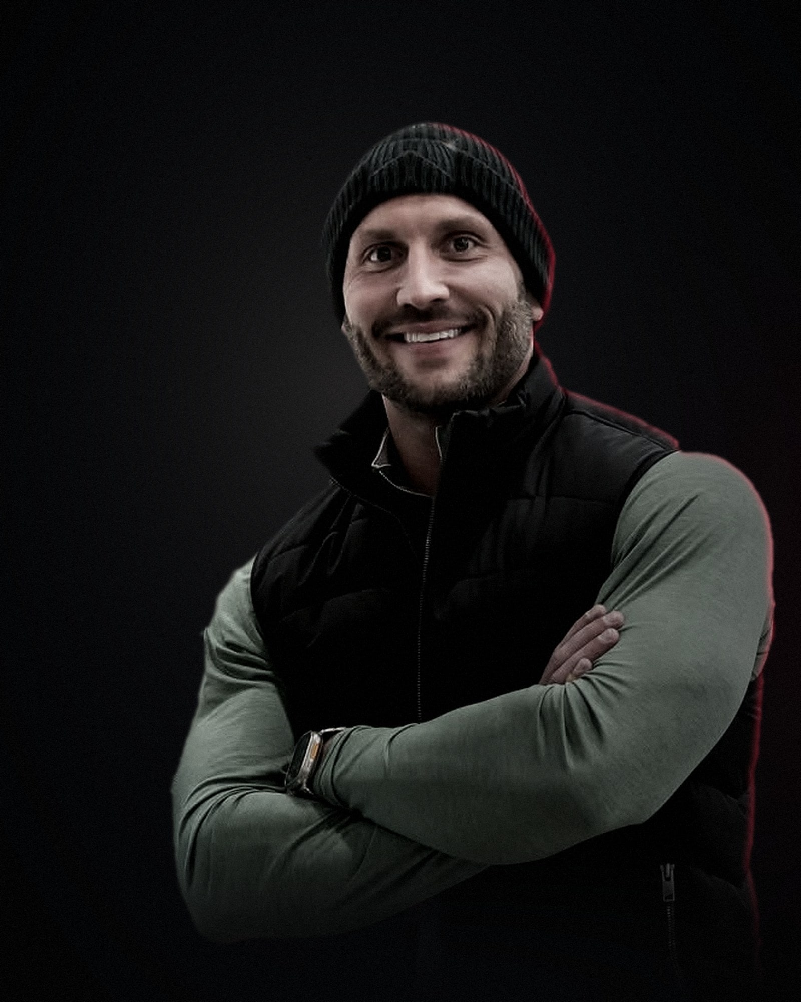 Brady Fedro, arms crossed, in a dark room lit by a single warm key light with a crimson rim.